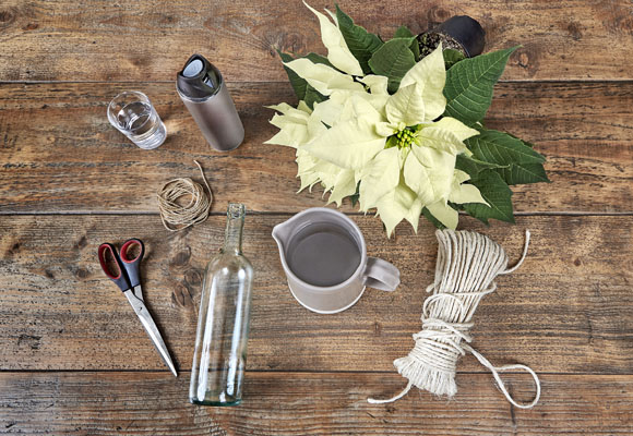 Un centro de Navidad con botellas y ponsettias