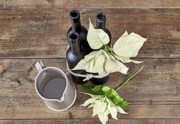 Un centro de Navidad con botellas y ponsettias